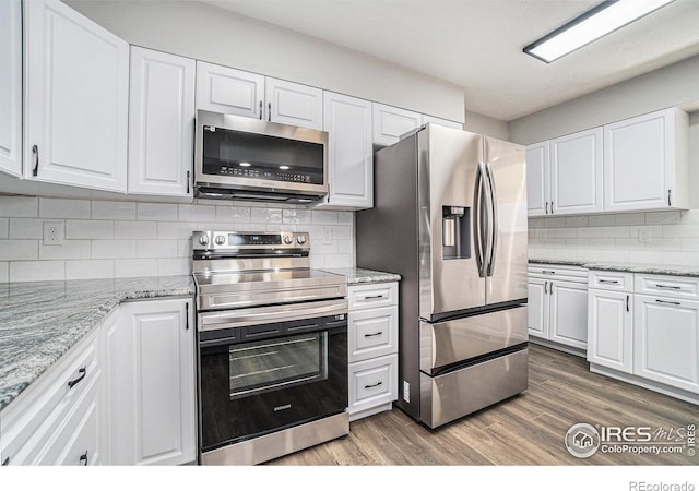 kitchen with hardwood / wood-style flooring, stainless steel appliances, backsplash, and white cabinets