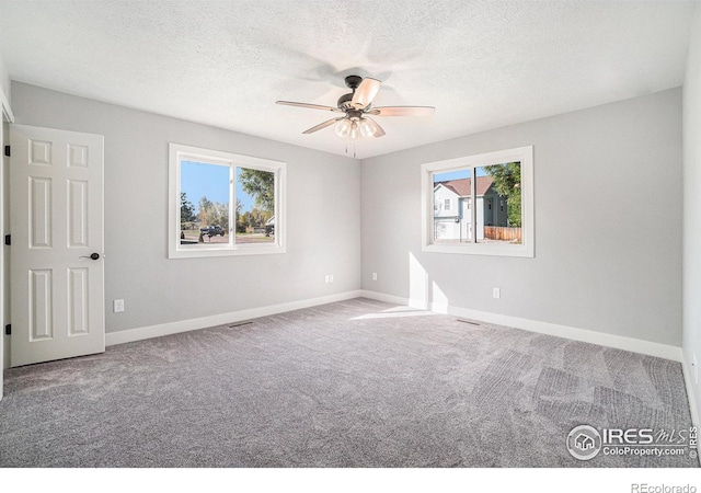 empty room featuring a textured ceiling, carpet floors, and ceiling fan