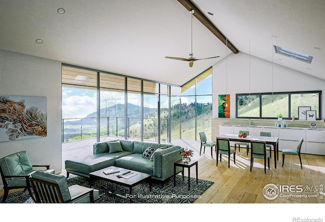 living room with beamed ceiling, light hardwood / wood-style flooring, a mountain view, and ceiling fan