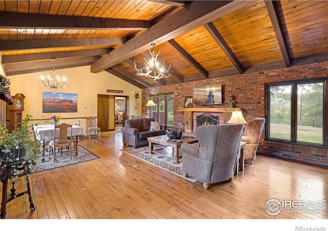 living room featuring light hardwood / wood-style floors, a notable chandelier, wood ceiling, and a brick fireplace