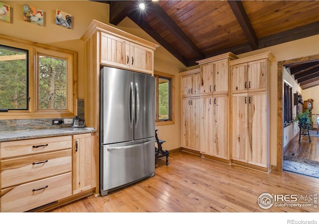 kitchen with light hardwood / wood-style floors, lofted ceiling with beams, light brown cabinetry, and stainless steel refrigerator