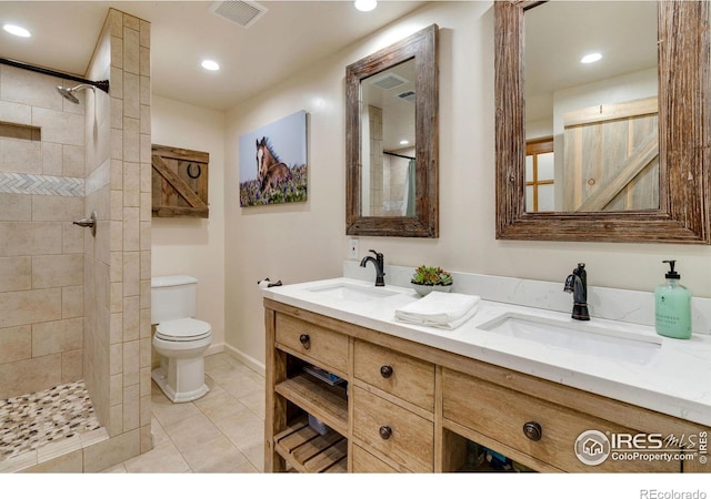 bathroom featuring vanity, a tile shower, toilet, and tile patterned flooring