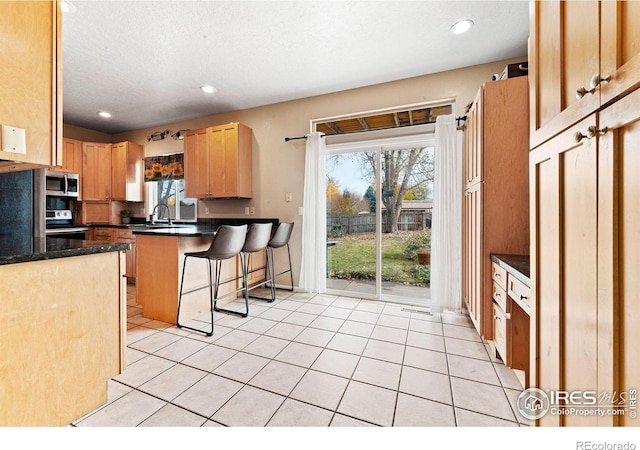 kitchen with sink, a breakfast bar, appliances with stainless steel finishes, and light tile patterned floors