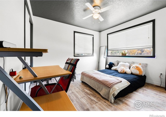 bedroom featuring ceiling fan, a textured ceiling, and light hardwood / wood-style flooring