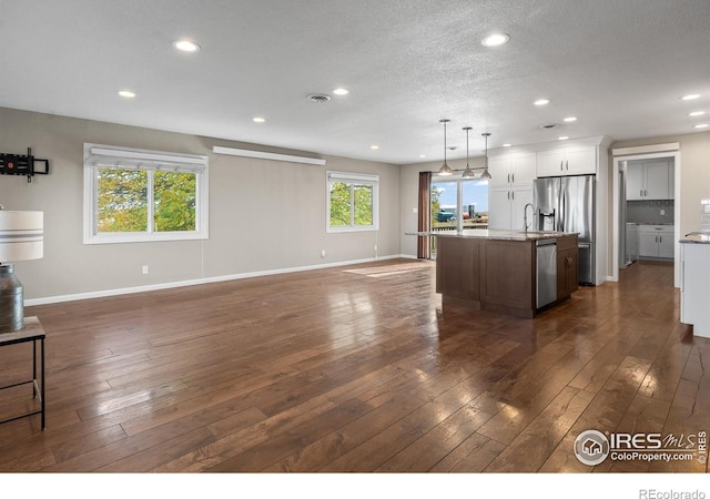 kitchen featuring a center island with sink, appliances with stainless steel finishes, decorative light fixtures, white cabinets, and sink