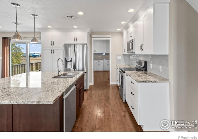 kitchen featuring white cabinets, appliances with stainless steel finishes, decorative light fixtures, decorative backsplash, and sink