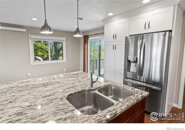 kitchen featuring light stone countertops, pendant lighting, white cabinets, and stainless steel fridge with ice dispenser