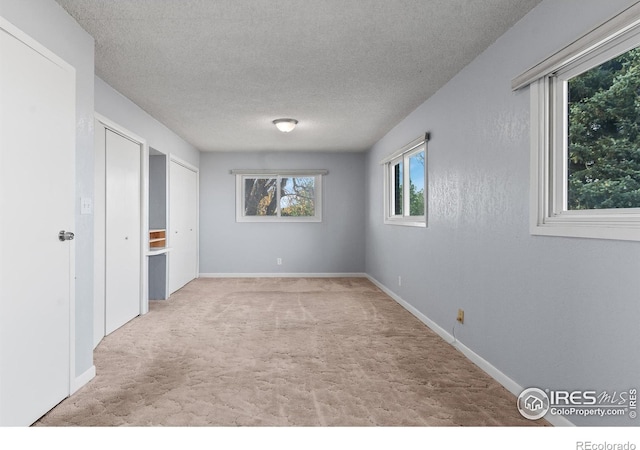 unfurnished room with light carpet and a textured ceiling