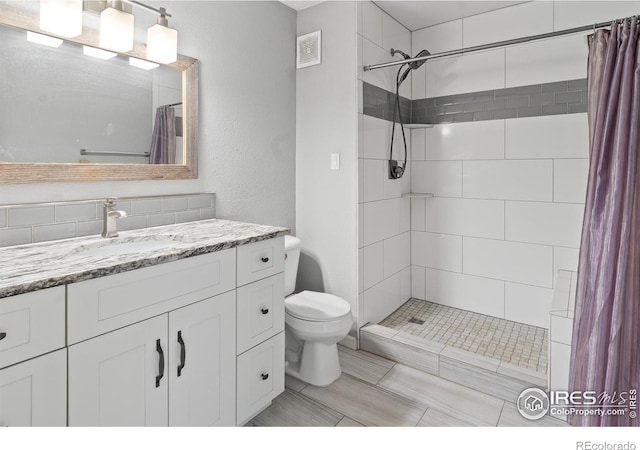 bathroom featuring toilet, vanity, and a shower with curtain