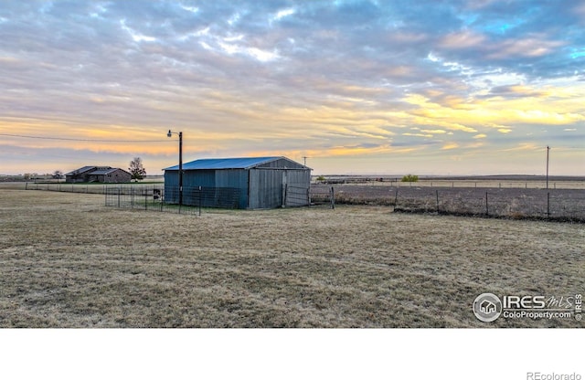 yard at dusk with a rural view and an outdoor structure