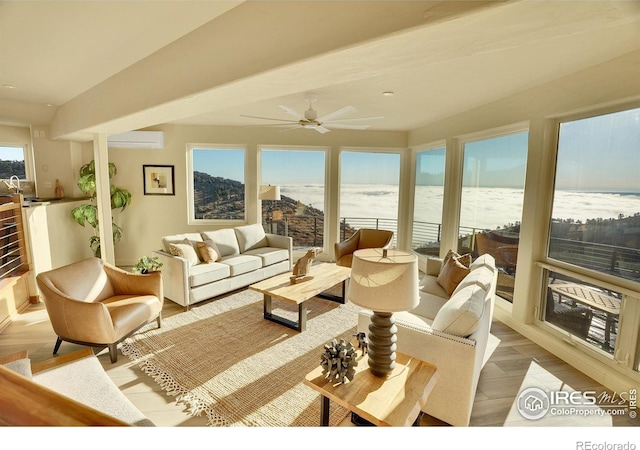 living room with a wall unit AC, light wood-type flooring, a healthy amount of sunlight, and a water view