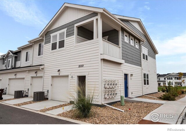 view of front of house with a balcony, a garage, and central AC unit