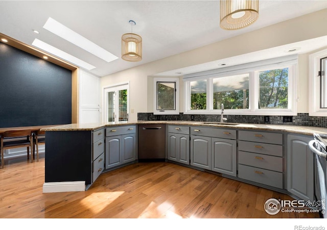 kitchen with gray cabinetry, appliances with stainless steel finishes, a skylight, sink, and light hardwood / wood-style floors