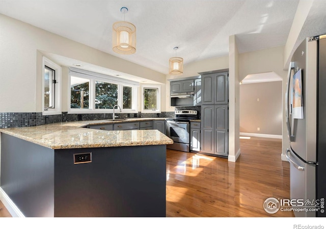 kitchen with kitchen peninsula, hanging light fixtures, appliances with stainless steel finishes, gray cabinets, and sink