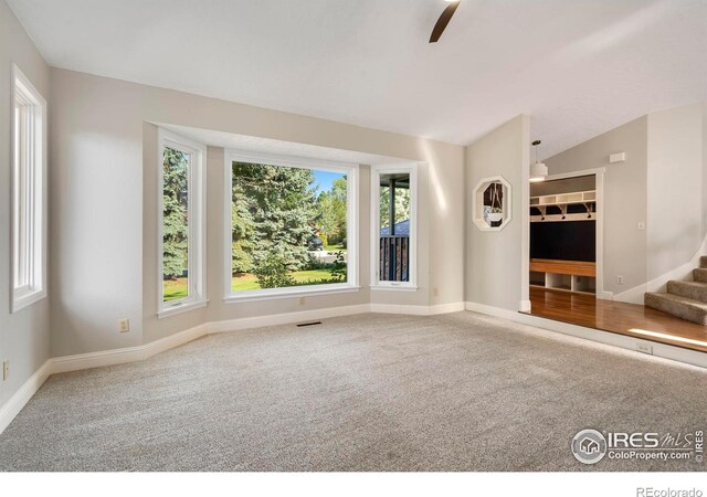 unfurnished living room featuring vaulted ceiling and carpet floors