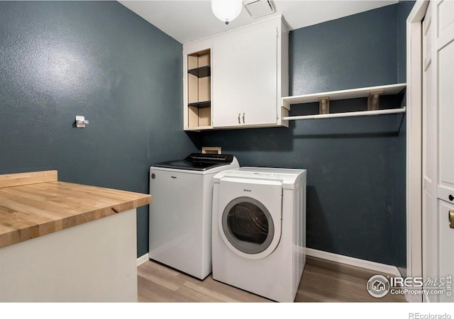 laundry room featuring independent washer and dryer, cabinets, and light hardwood / wood-style floors