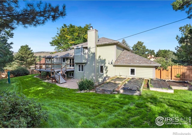 rear view of property featuring a wooden deck, a patio, and a lawn