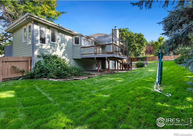 rear view of house with a wooden deck and a lawn