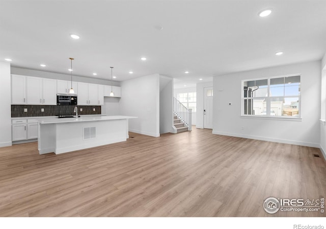 kitchen with white cabinetry, light hardwood / wood-style flooring, and hanging light fixtures