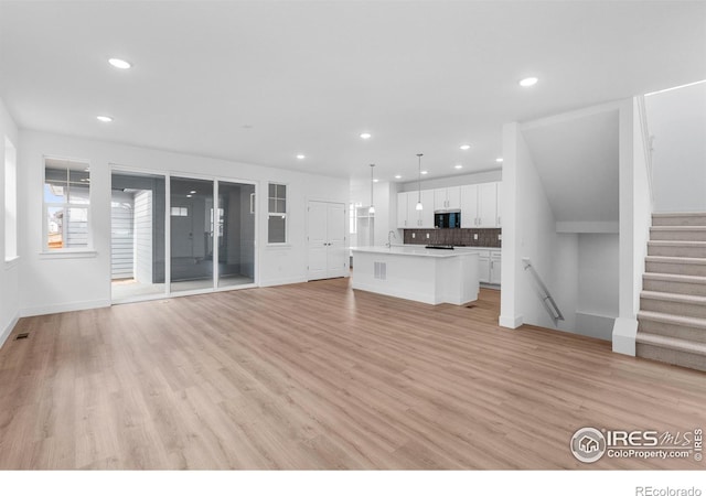 unfurnished living room with sink and light hardwood / wood-style flooring