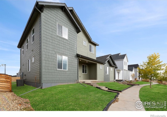 view of front of house with a front lawn and central AC unit