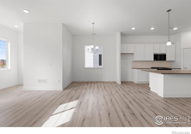 kitchen featuring white cabinets, light hardwood / wood-style flooring, pendant lighting, and an inviting chandelier