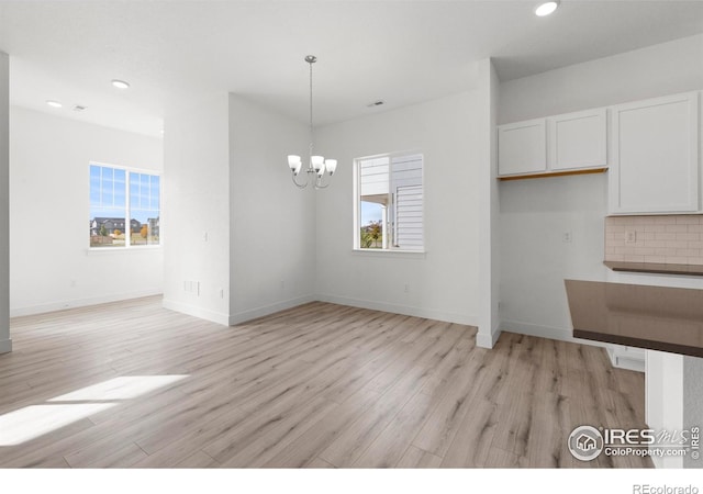 unfurnished dining area with light hardwood / wood-style flooring and a chandelier