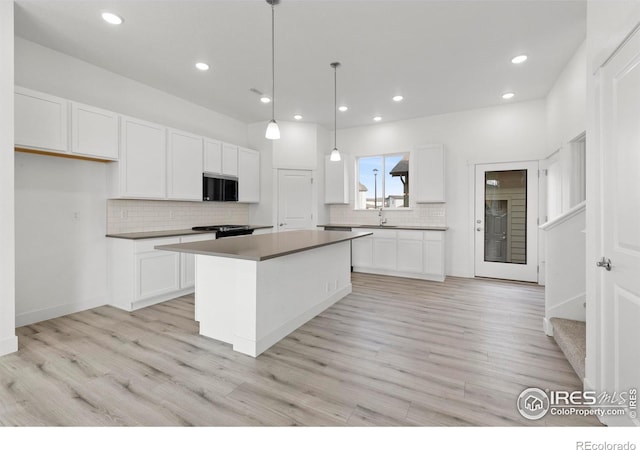 kitchen featuring light wood-type flooring, pendant lighting, a kitchen island, and white cabinets