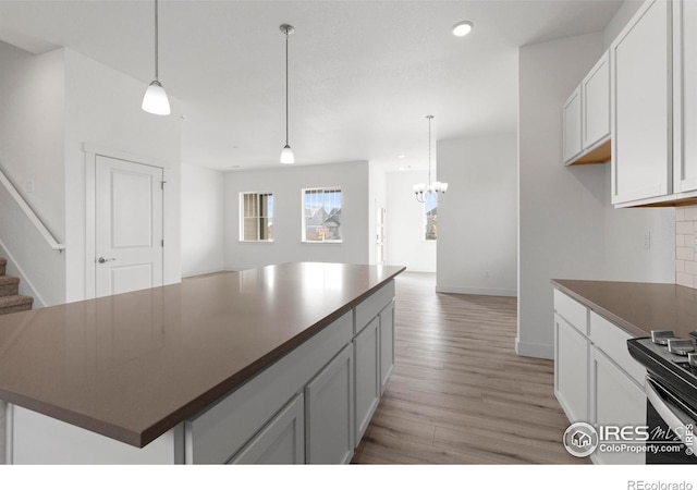 kitchen featuring light hardwood / wood-style flooring, white cabinets, decorative light fixtures, and a kitchen island