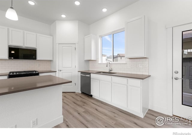 kitchen with sink, light hardwood / wood-style floors, stainless steel appliances, decorative light fixtures, and white cabinets