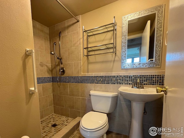 bathroom featuring toilet, tile walls, and a tile shower