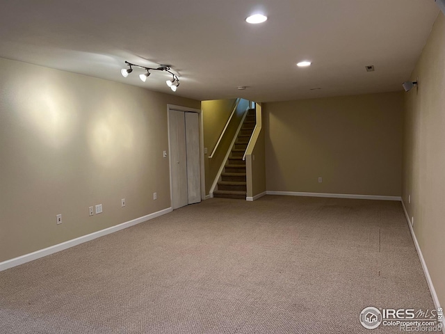 basement featuring rail lighting and carpet