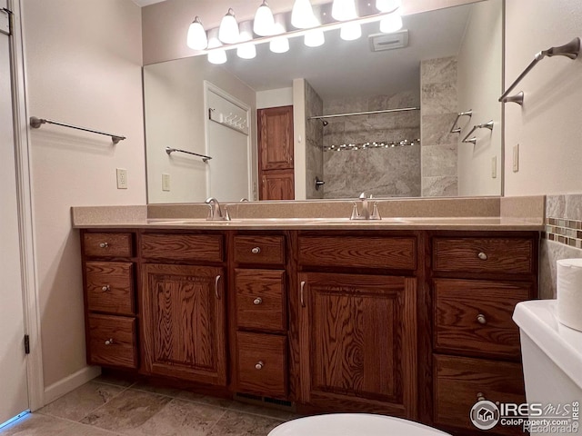 bathroom with toilet, vanity, and tiled shower