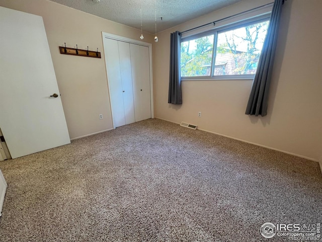 unfurnished bedroom featuring carpet floors, a textured ceiling, and a closet