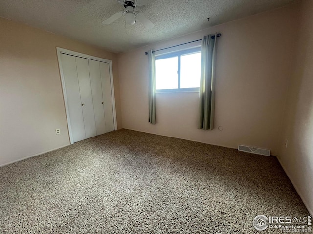 unfurnished bedroom with a closet, a textured ceiling, carpet flooring, and ceiling fan