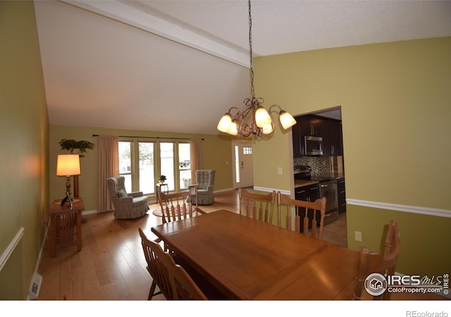 dining room with wood-type flooring, vaulted ceiling with beams, and a notable chandelier