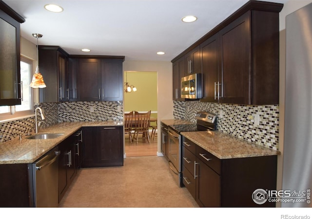 kitchen featuring pendant lighting, appliances with stainless steel finishes, sink, and backsplash