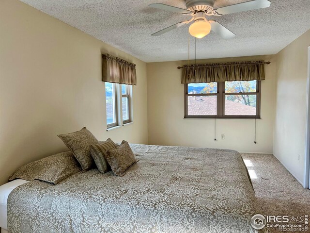 bedroom with a textured ceiling, carpet floors, and ceiling fan