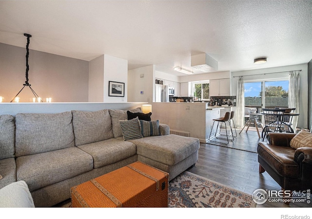 living room with a textured ceiling, hardwood / wood-style flooring, and a chandelier