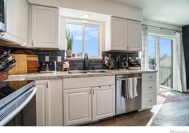 kitchen with appliances with stainless steel finishes, sink, backsplash, dark hardwood / wood-style flooring, and white cabinets