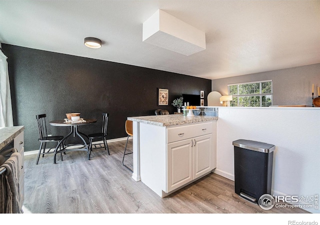 kitchen featuring light hardwood / wood-style flooring, white cabinetry, and kitchen peninsula