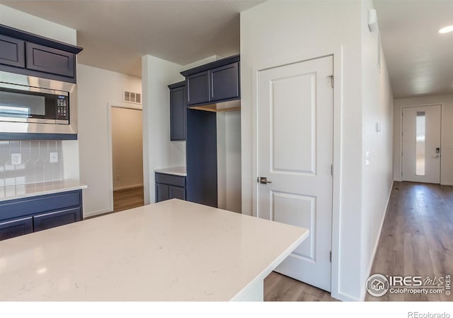 kitchen featuring stainless steel microwave and light wood-type flooring