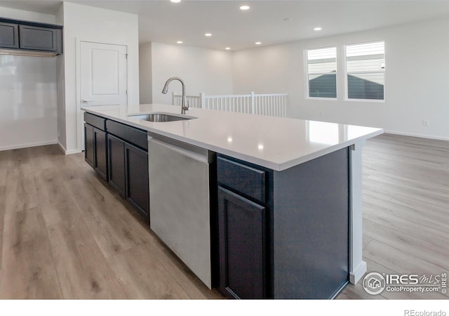 kitchen with sink, dishwasher, an island with sink, and light wood-type flooring