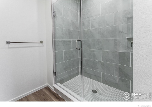 bathroom with wood-type flooring and a shower with door