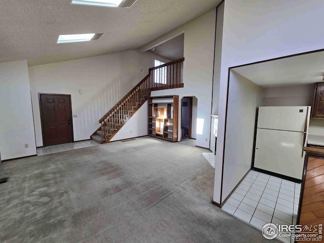 unfurnished living room featuring a textured ceiling, a wealth of natural light, and light colored carpet