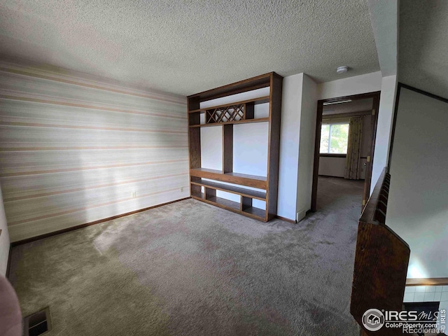 unfurnished room featuring a textured ceiling and carpet