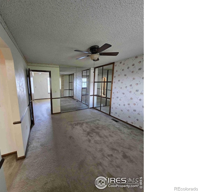 carpeted spare room with ceiling fan and a textured ceiling