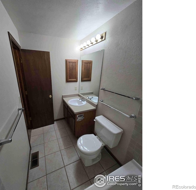 bathroom featuring vanity, a textured ceiling, toilet, and tile patterned flooring