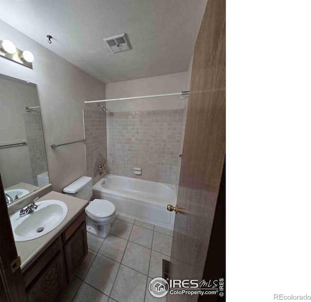 full bathroom featuring a textured ceiling, toilet, tile patterned floors, tiled shower / bath, and vanity