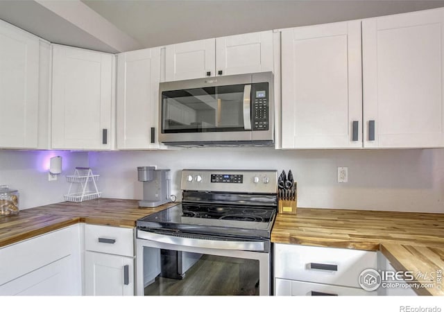 kitchen with stainless steel appliances, wood counters, and white cabinets